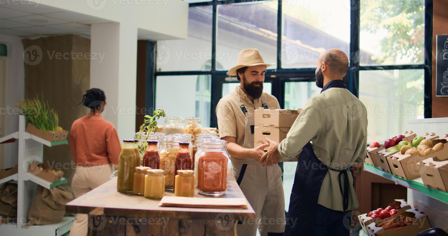 Farmer supplies zero waste eco shop with freshly harvested fruits and veggies, bringing crates filled with new produce to local vendor. Storekeeper and farming owner shake hands. Tripod shot. photo