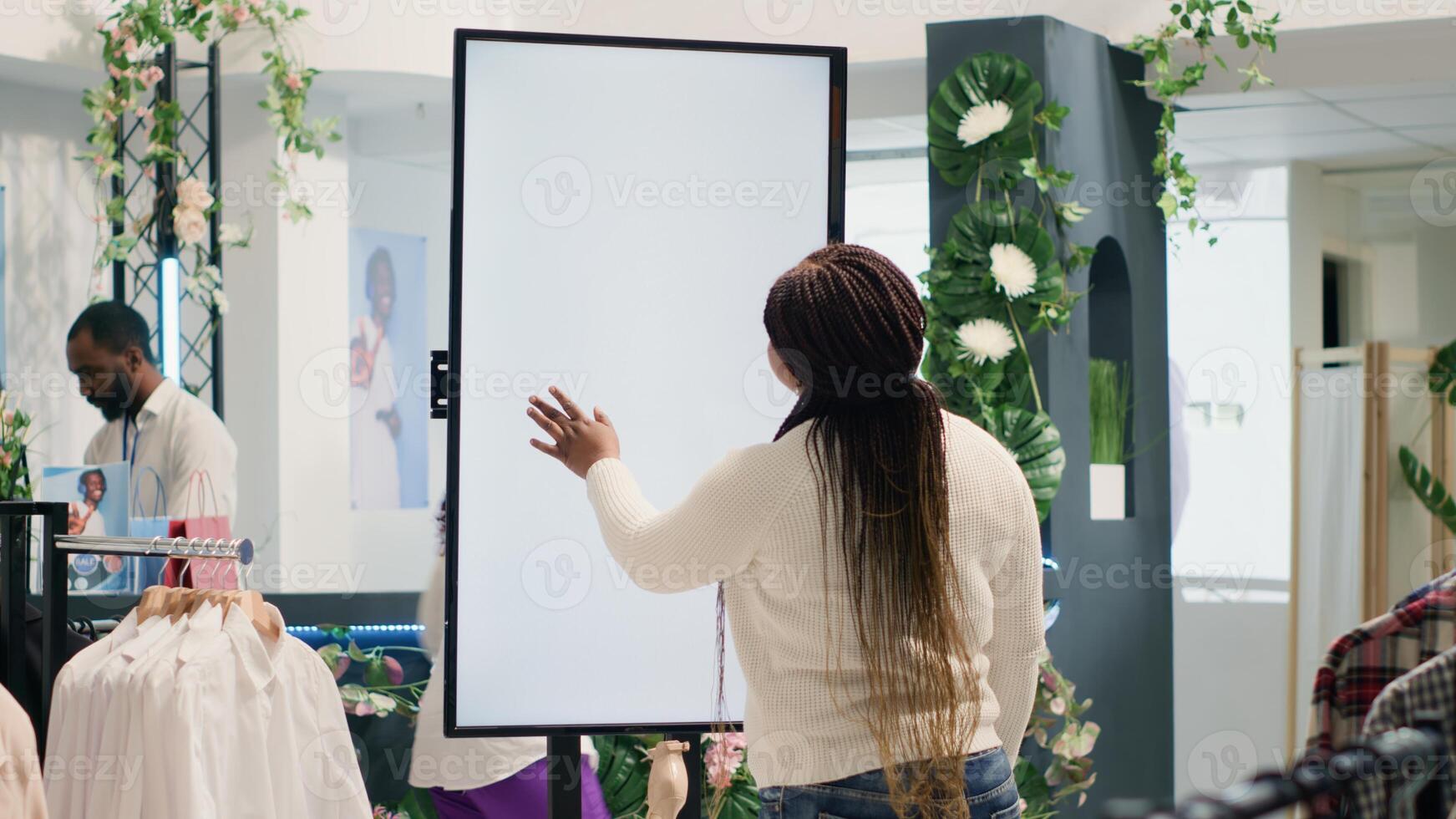 Customer in high tech thrift shop using digital isolated screen to find ideal outfit. BIPOC client in cheap second hand clothing store doing shopping using augmented reality kiosk photo