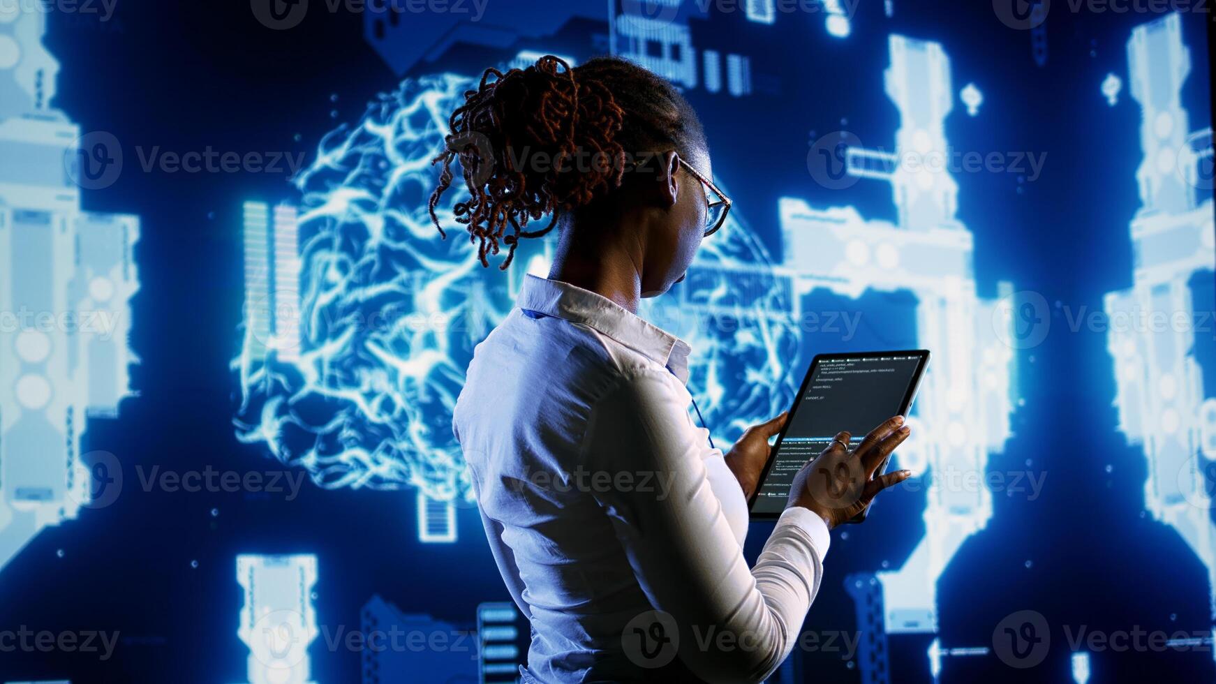 African american scientist programming scripts on tablet, employing AI machine learning infrastructure. Licensed employee manipulates lines of code for artificial intelligence applications development photo