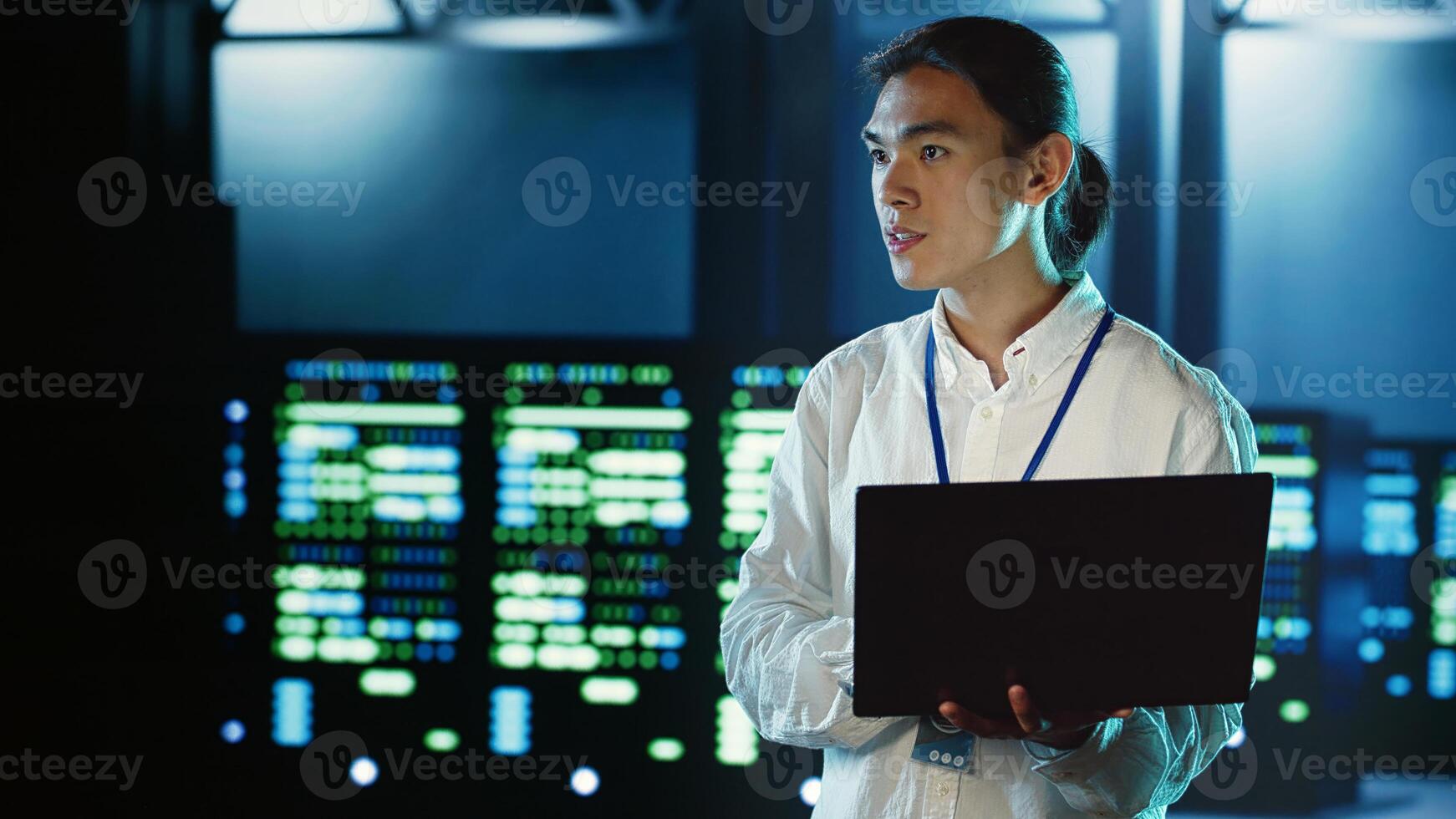 Trained employee strolling through server rows providing processing resources for different workloads. Asian dilligent worker monitoring supercomputers tasked with solving complex operations photo