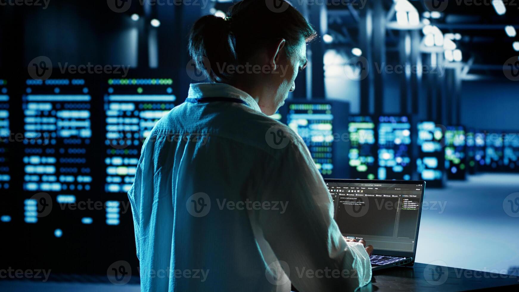 Experienced engineer running programming code on laptop, troubleshooting and updating data center equipment designed to accommodate server clusters, networking systems and storage arrays photo