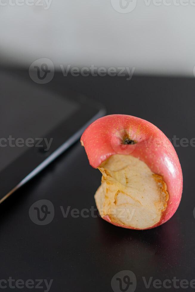 Bitten Red Apple Next to Tablet photo