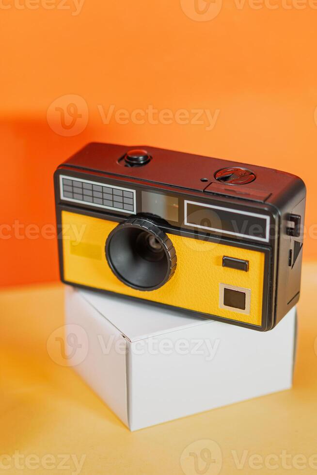 Retro Camera on White Box Against Orange Background photo