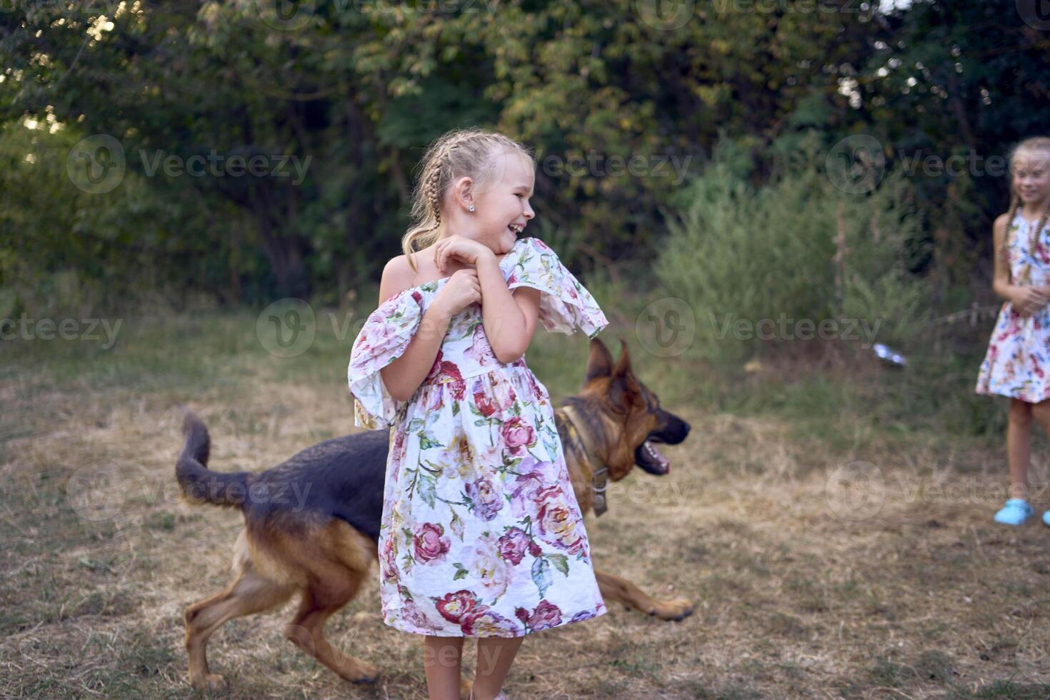 little girls sisters play with german shepherd dog during easter picnic in the garden photo