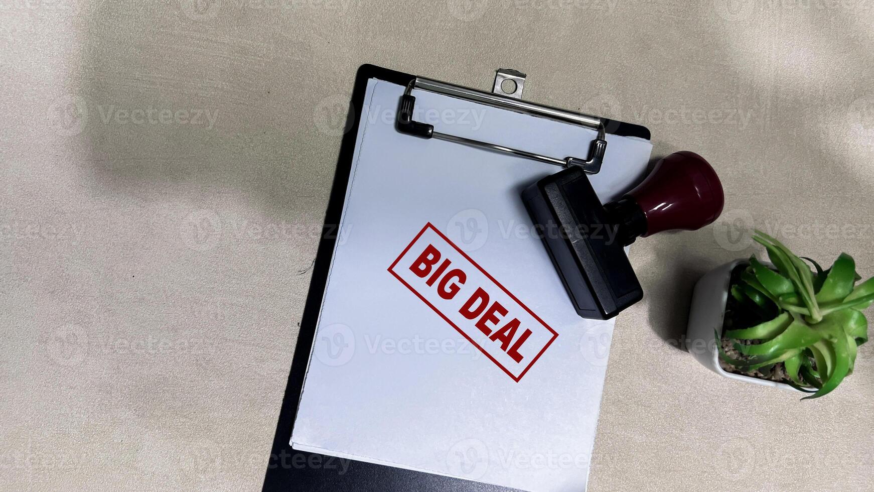 Red Handle Rubber Stamper and Big Deal text on a paperwork isolated on wooden background photo