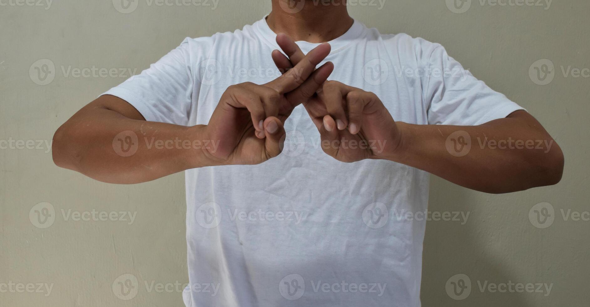 Young man showing fingers gestures, having fun, leading pleasant in american sign language photo