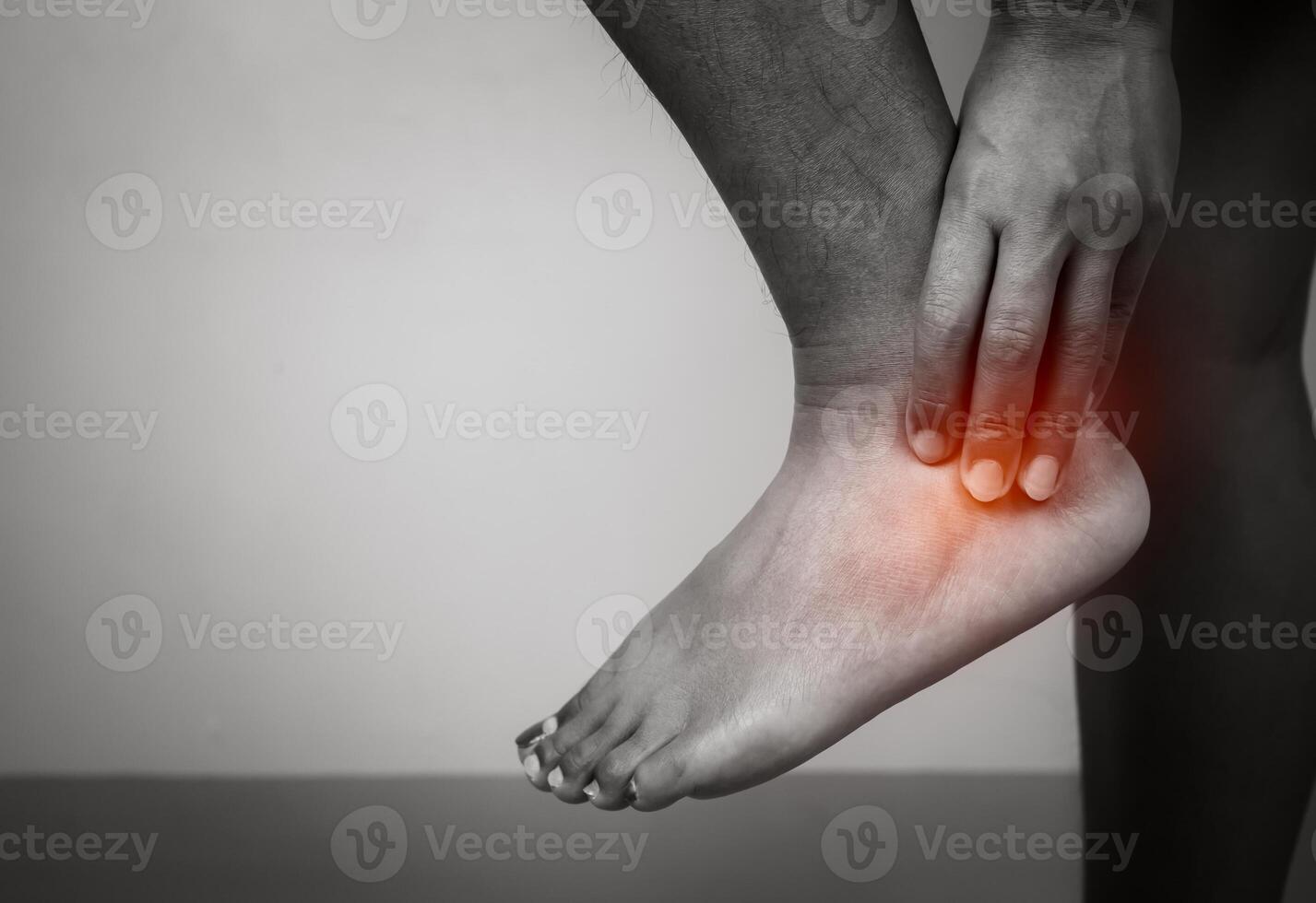 Woman with acute pain ankle with leg pain on gray background, Ankle and leg treatment, Female massaging her ankle muscle spasm, Healthcare and medical concept, Injuries and medical concept. photo