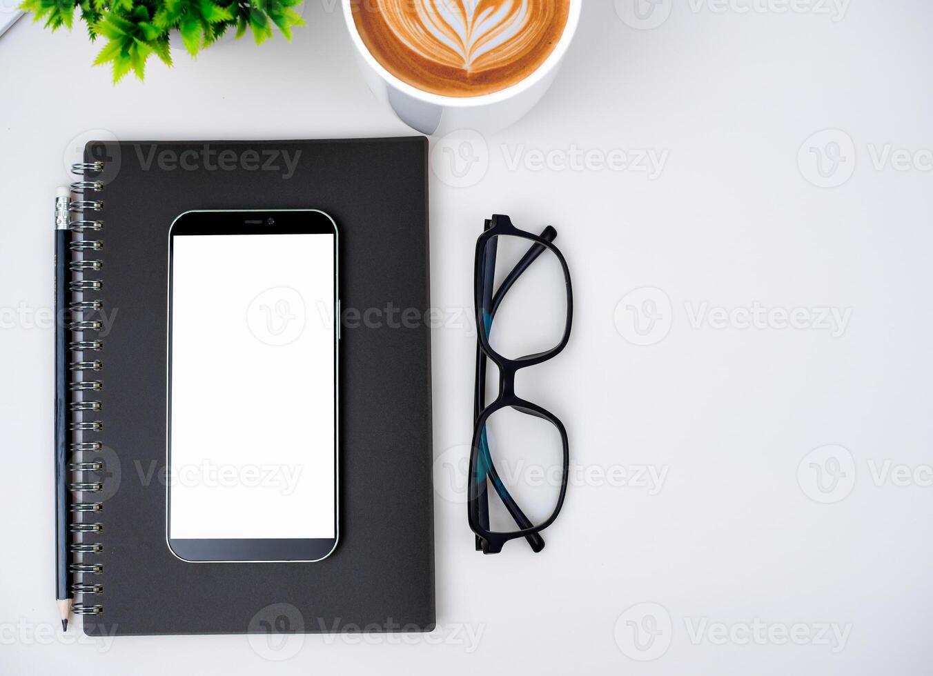 Top view of mock up modern workspace with blank screen smartphone, Coffee cup, Notebook, Pencil, Glasses. Office situation with keyboard and accessories isolated on white. Copy space, Flat lay. photo