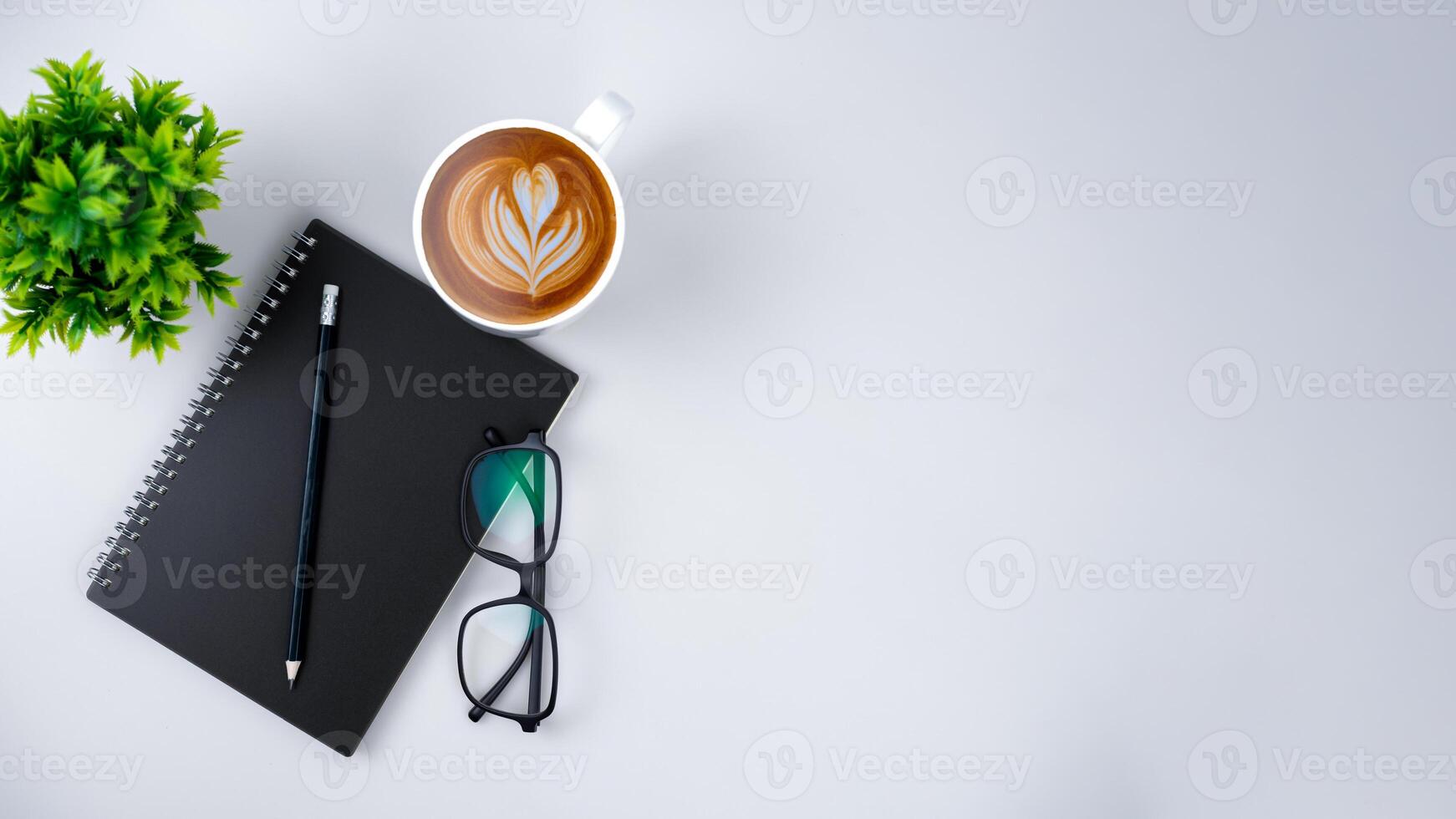 Top view white workspace office desk with office supplies. Flat lay work table with black notebook, Green leaf and coffee cup, Copy space for your advertising content. photo