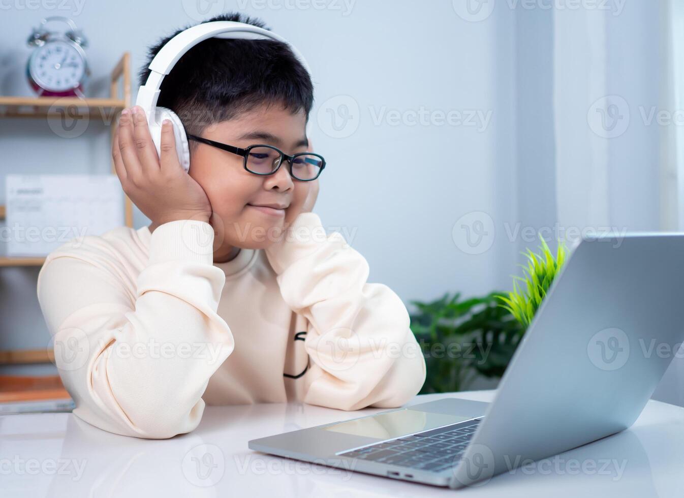 Asian student boy using headphones and computer learning. Educational of tech concept, Staying at home, Presenting a modern educational way of life. Virtual internet online class from school teacher. photo