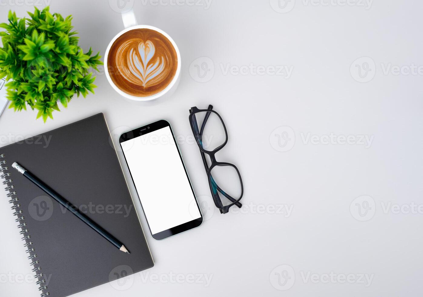 Top view of mock up modern workspace with blank screen smartphone, Coffee cup, Notebook, Pencil, Glasses. Office situation with keyboard and accessories isolated on white. Copy space, Flat lay. photo
