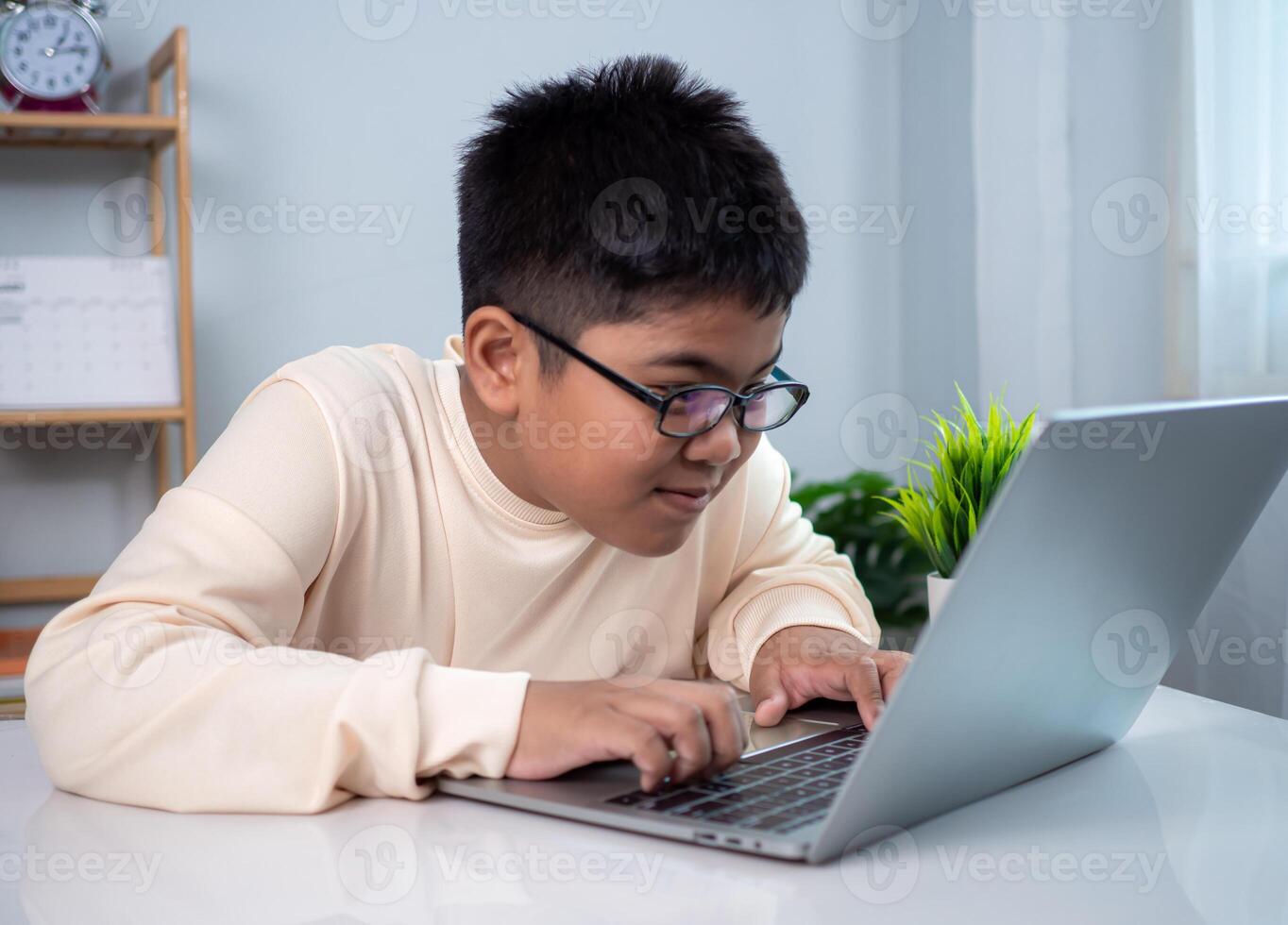 Little Asian boy student using computer laptop learning. Educational of tech concept, Staying at home, Presenting a modern educational way of life. Virtual internet online class from school teacher. photo