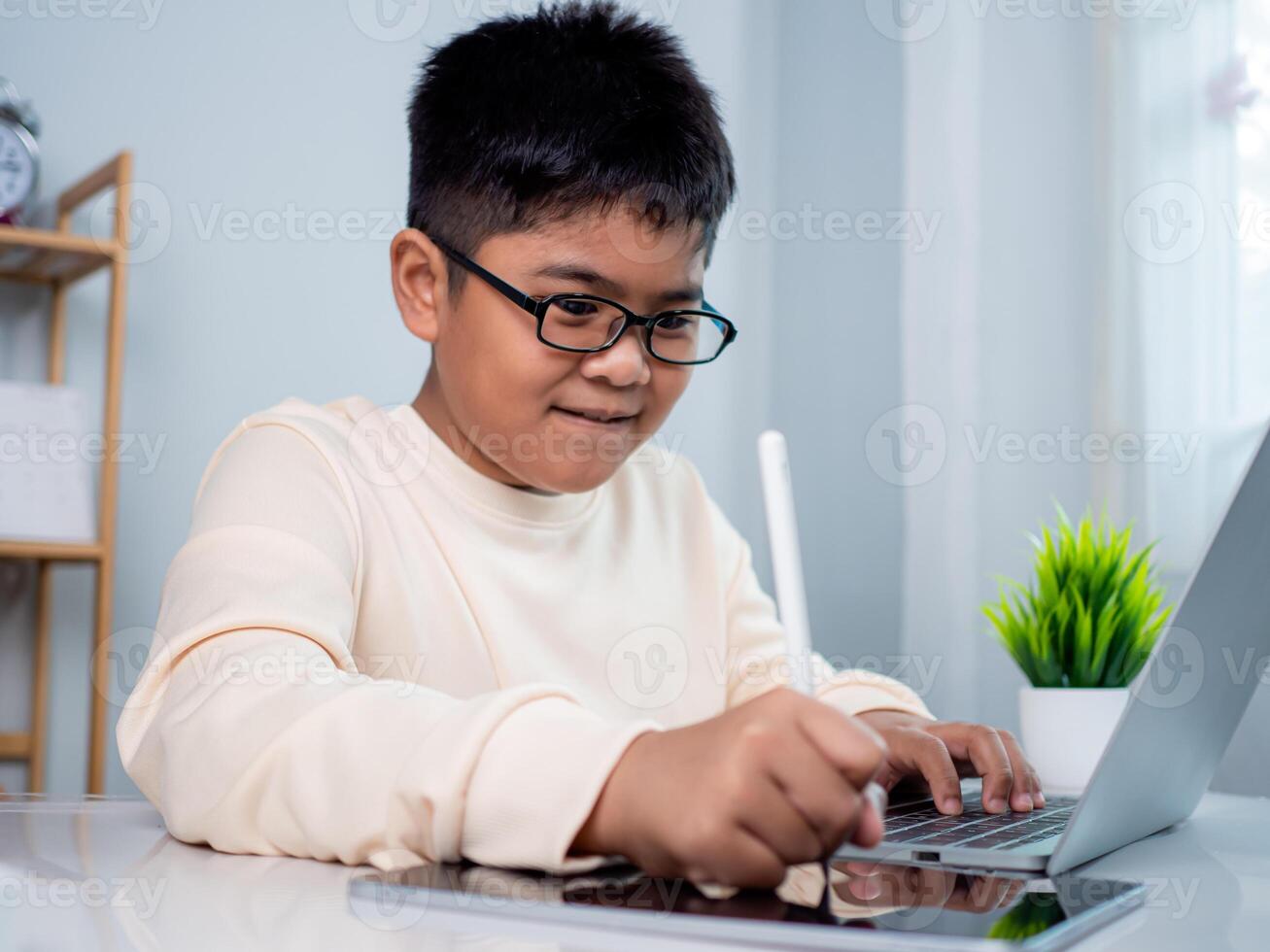 Little Asian boy student using computer laptop learning. Educational of tech concept, Staying at home, Presenting a modern educational way of life. Virtual internet online class from school teacher. photo