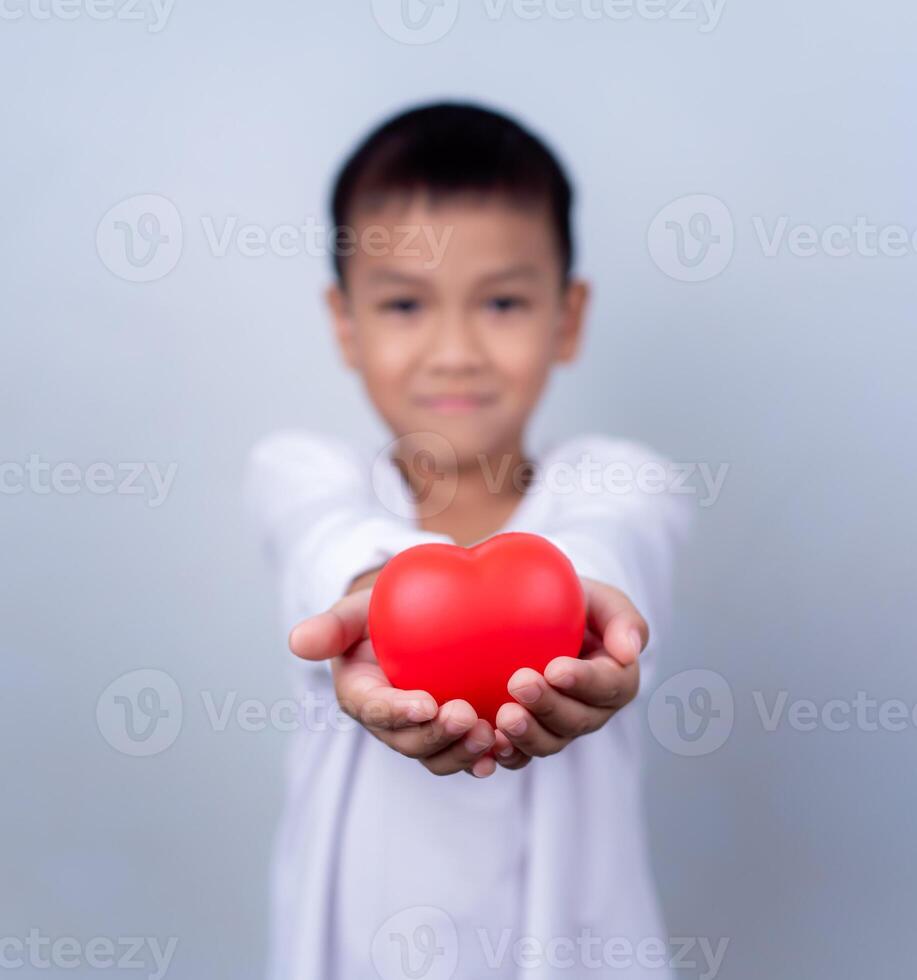 Portrait of Asian little boy child holding red heart sign on white background. photo
