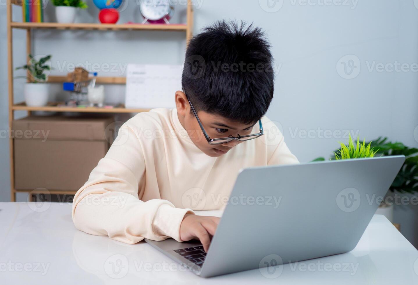 Educational of tech concept, Staying at home, Little Asian boy student using computer laptop learning, Presenting a modern educational way of life, Virtual internet online class from school teacher. photo