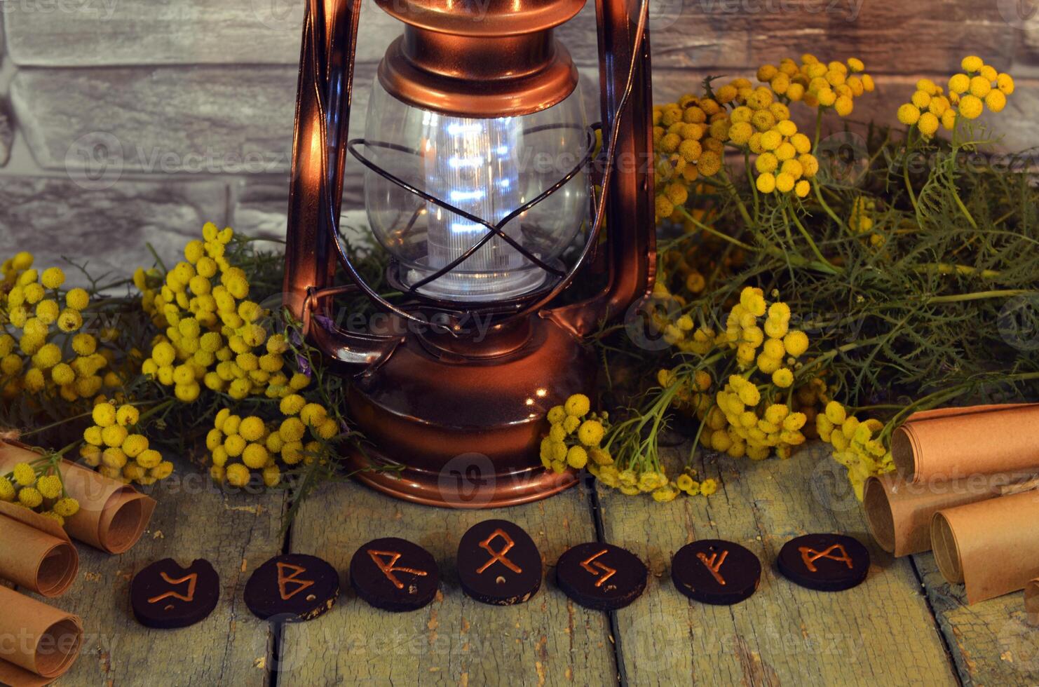 Mystic still life with old lantern, runes, tansy flowers and witchy ritual objects on wooden altar table. Occult, esoteric, wicca, Halloween and gothic concept. photo