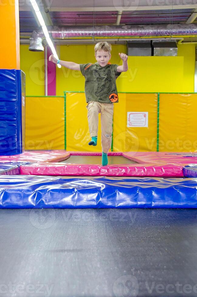Happy active emotional preteen boy bouncing on trampoline photo