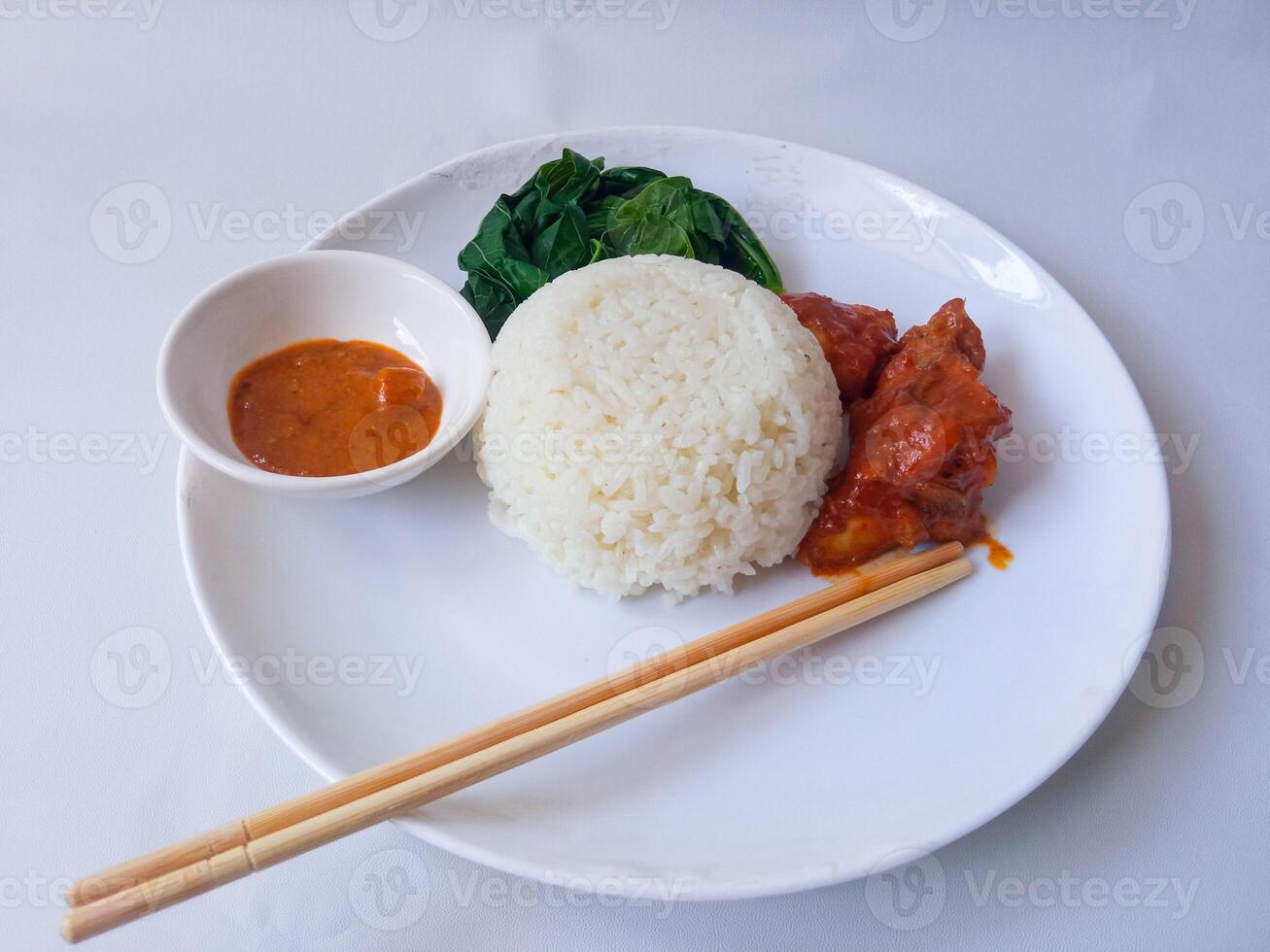 rice with padang rendang chicken side dish and cassava leaf vegetables on a white plate isolate on white photo