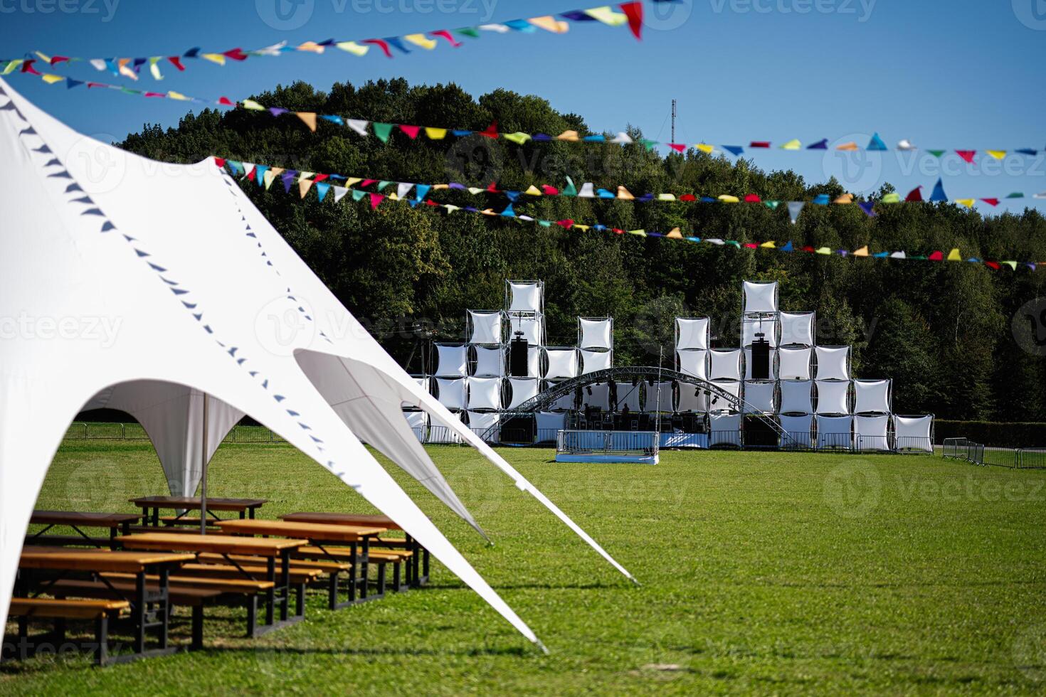 Outdoor festival setup with stage and white tents in a green field photo