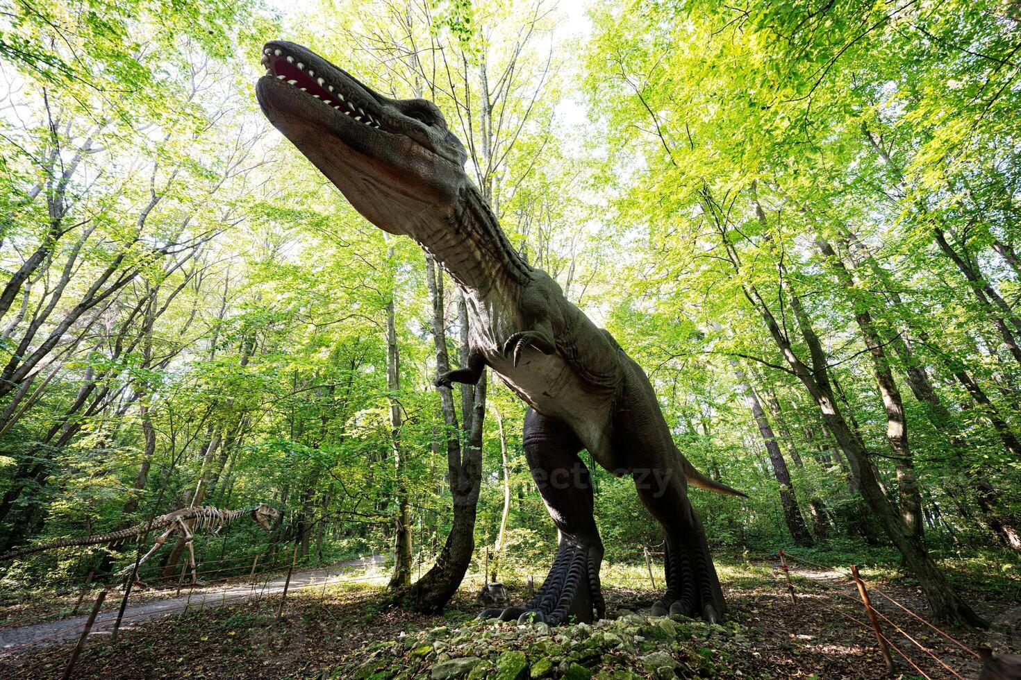 Realistic dinosaur sculpture in lush forest setting photo