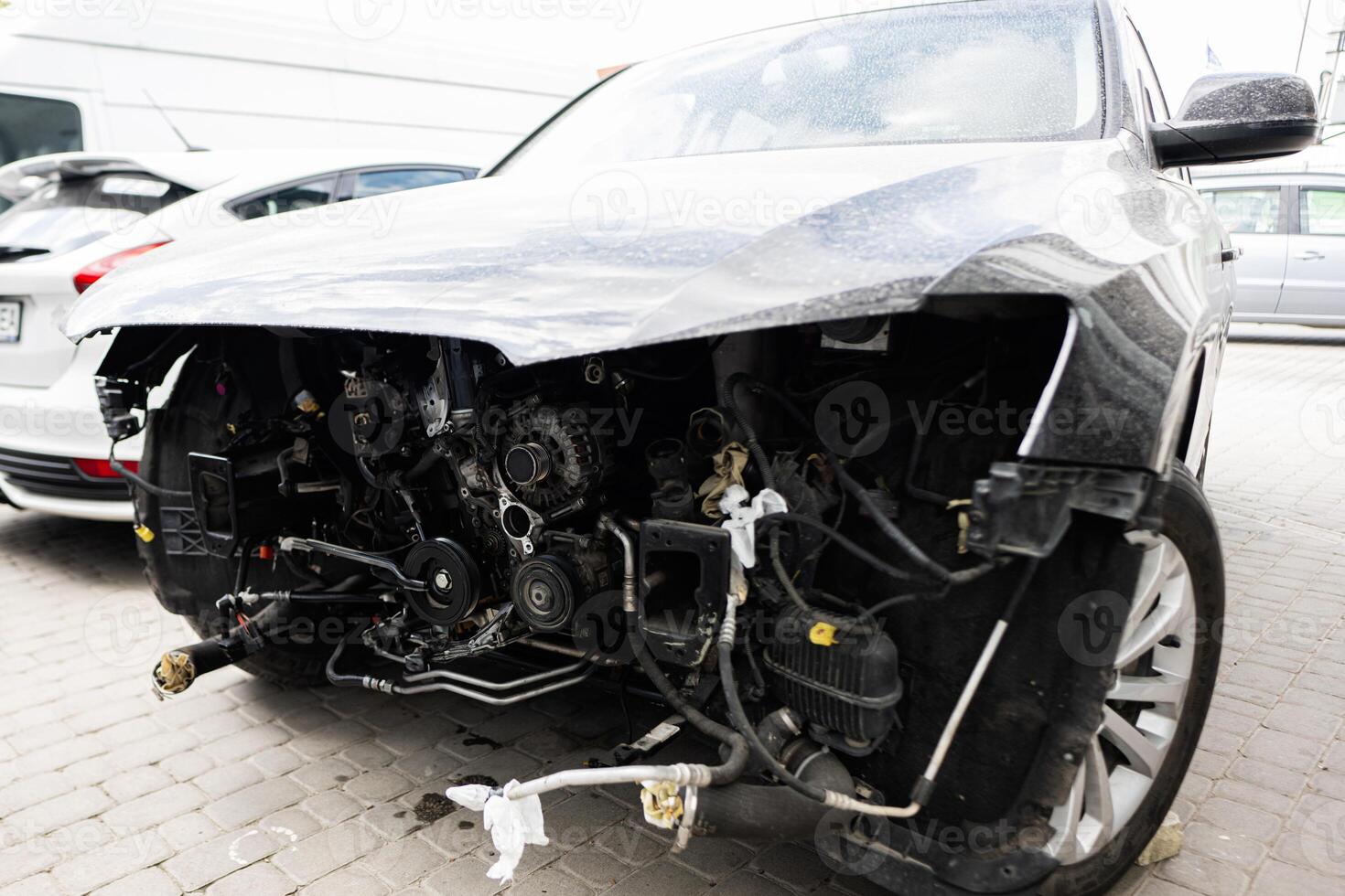 Front of damaged car showing exposed engine components photo