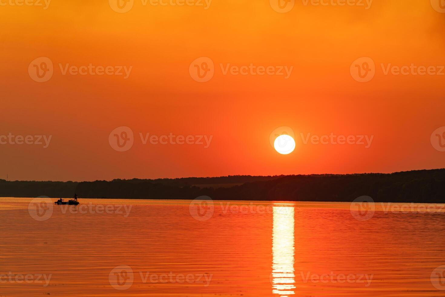 Beautiful sunset above the big lake or sea. Sunset beach. Orange sky. Boat in the middle of deep water. Nature concept photo