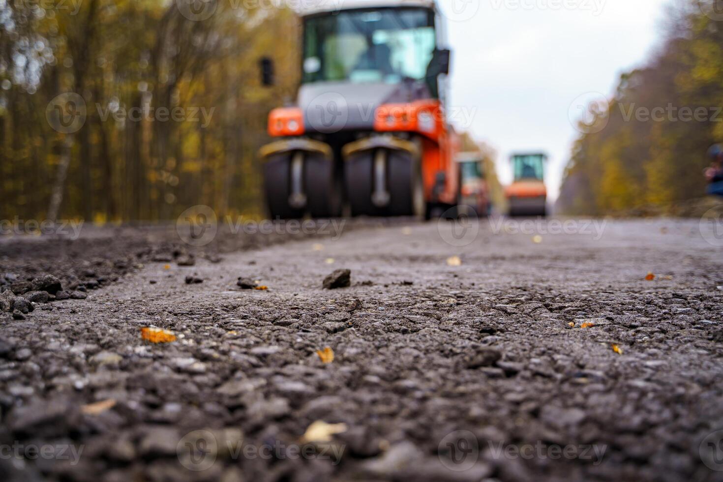 Workers operating asphalt paver machine during road construction. Close view on the road roller working on the new road construction site photo