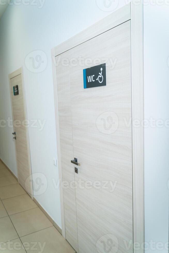 Perspective of a long corridor in office building. Doors of washrooms in hallway. Doors in office with wc signs. Entrance to restrooms in a factory photo