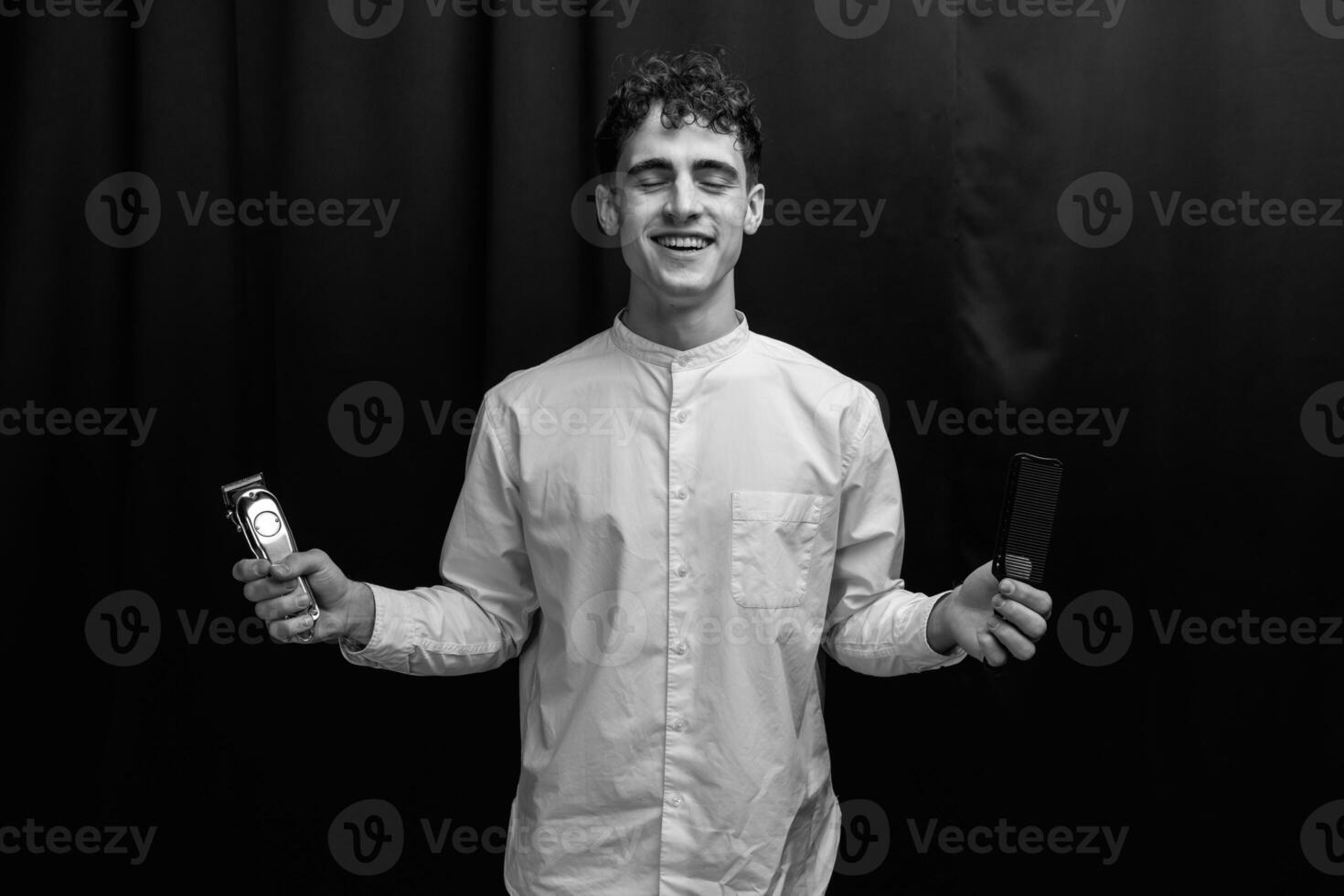 Barber holds in his hands a clipper and a comb photo