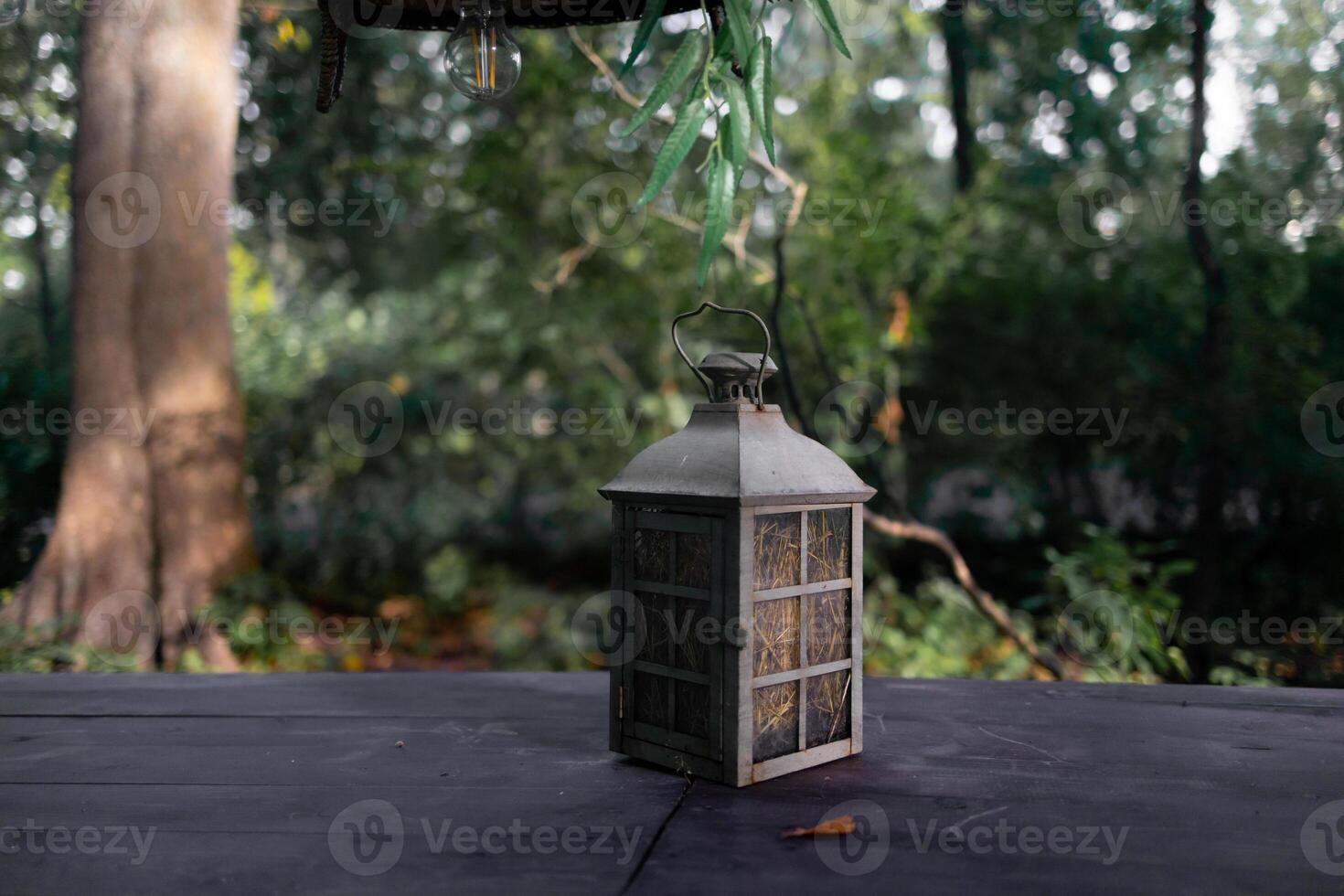 A beautiful decoration in the form of a large lantern and candlestick stands on a table illuminated photo