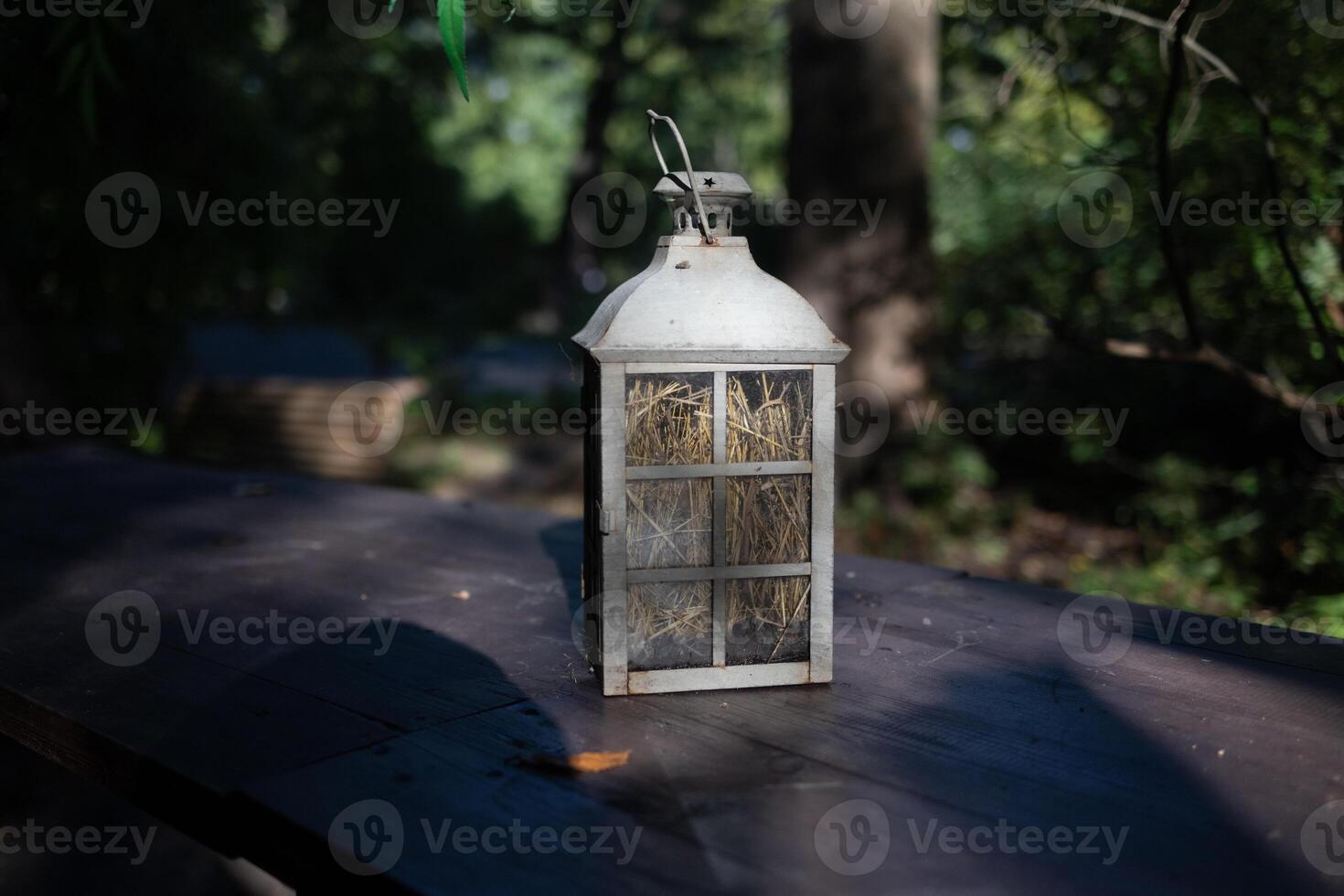 A beautiful decoration in the form of a large lantern and candlestick stands on a table illuminated photo