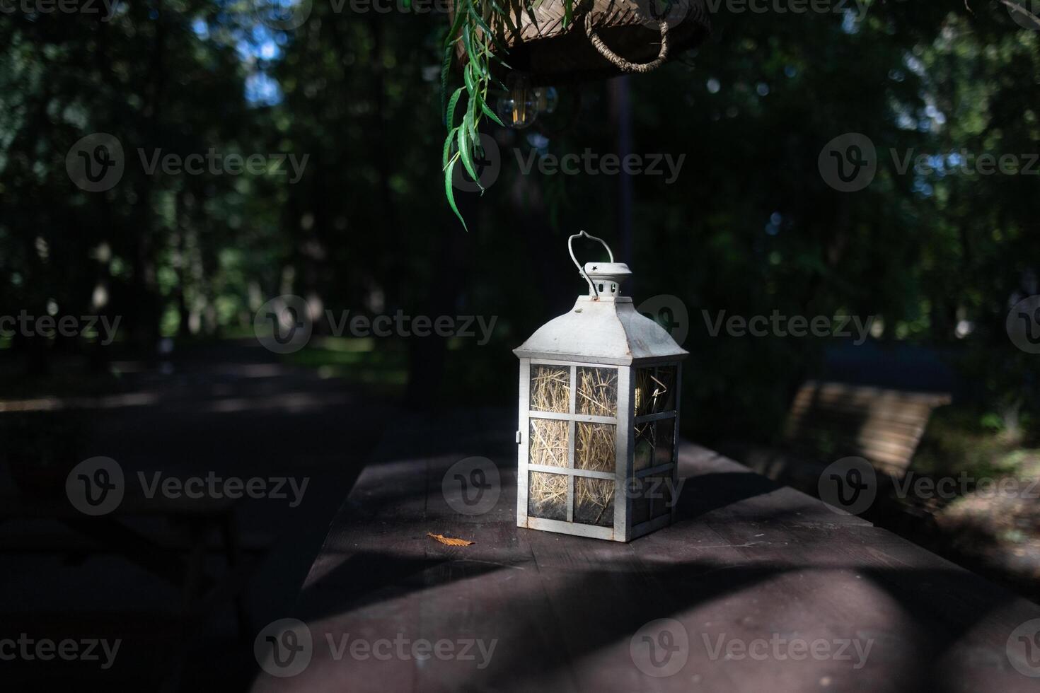 A beautiful decoration in the form of a large lantern and candlestick stands on a table illuminated photo