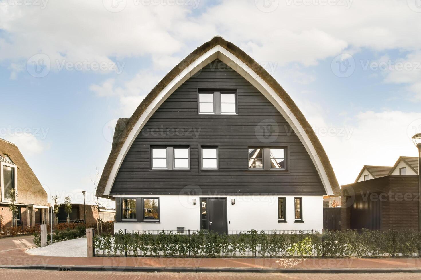 A house with a triangular shaped roof and a white fence photo