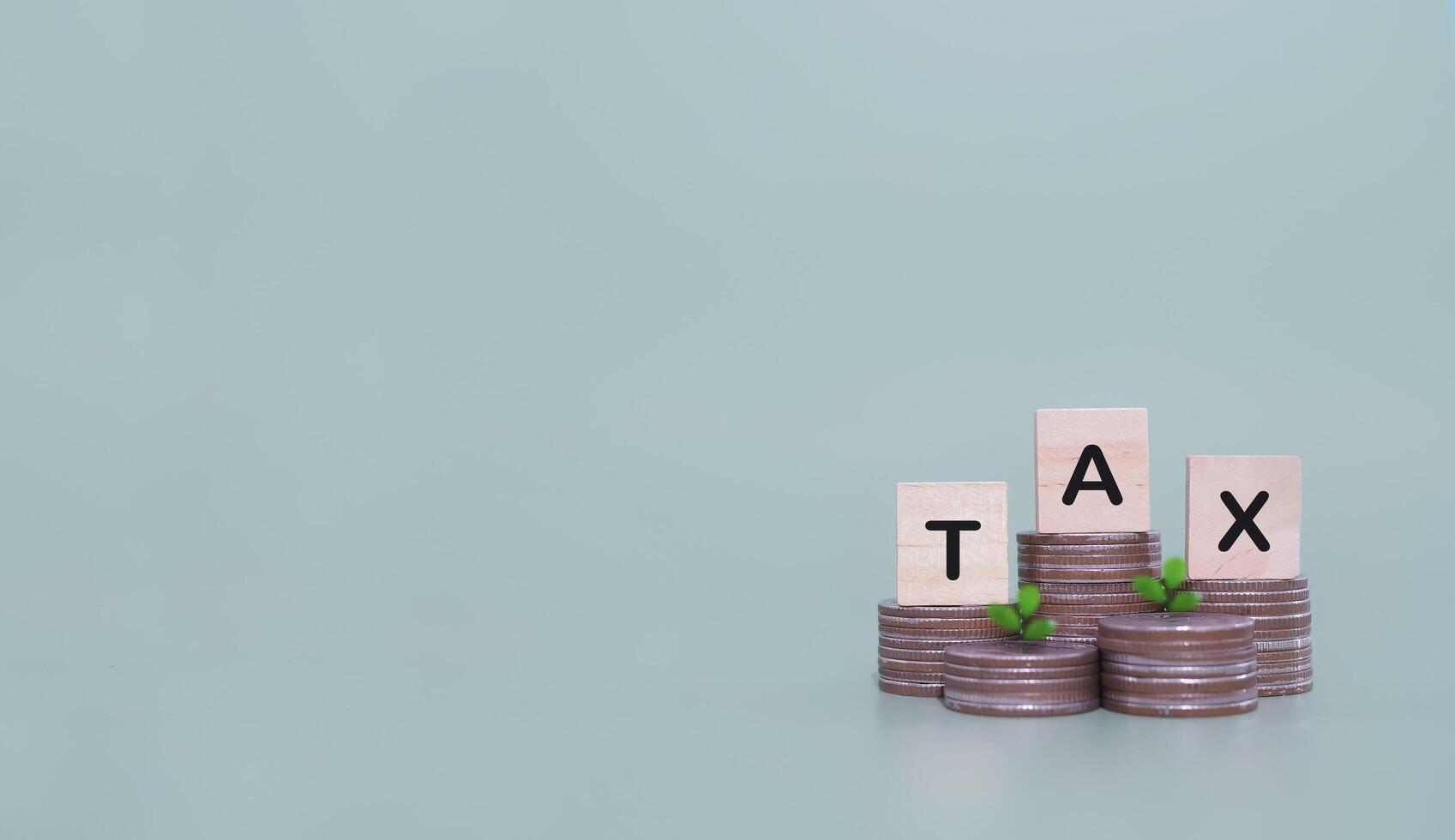 Wooden blocks with the word TAX on stack of coins. The concept of saving money for payment tax in future photo