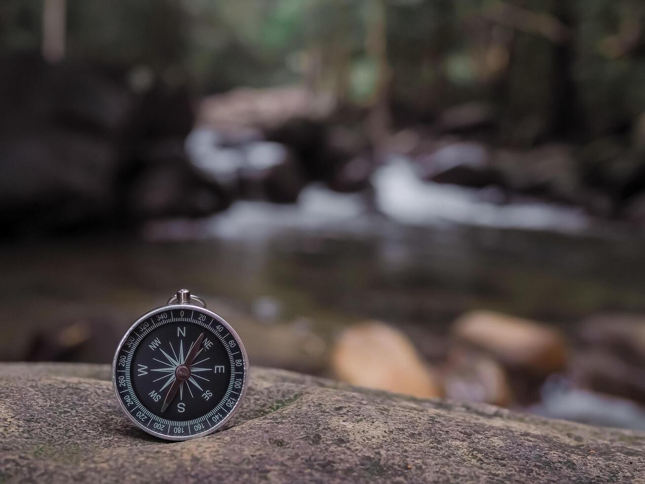 Compass on the rock with waterfall as background. The concept of world tourism day, Searching the right directions and Travel photo