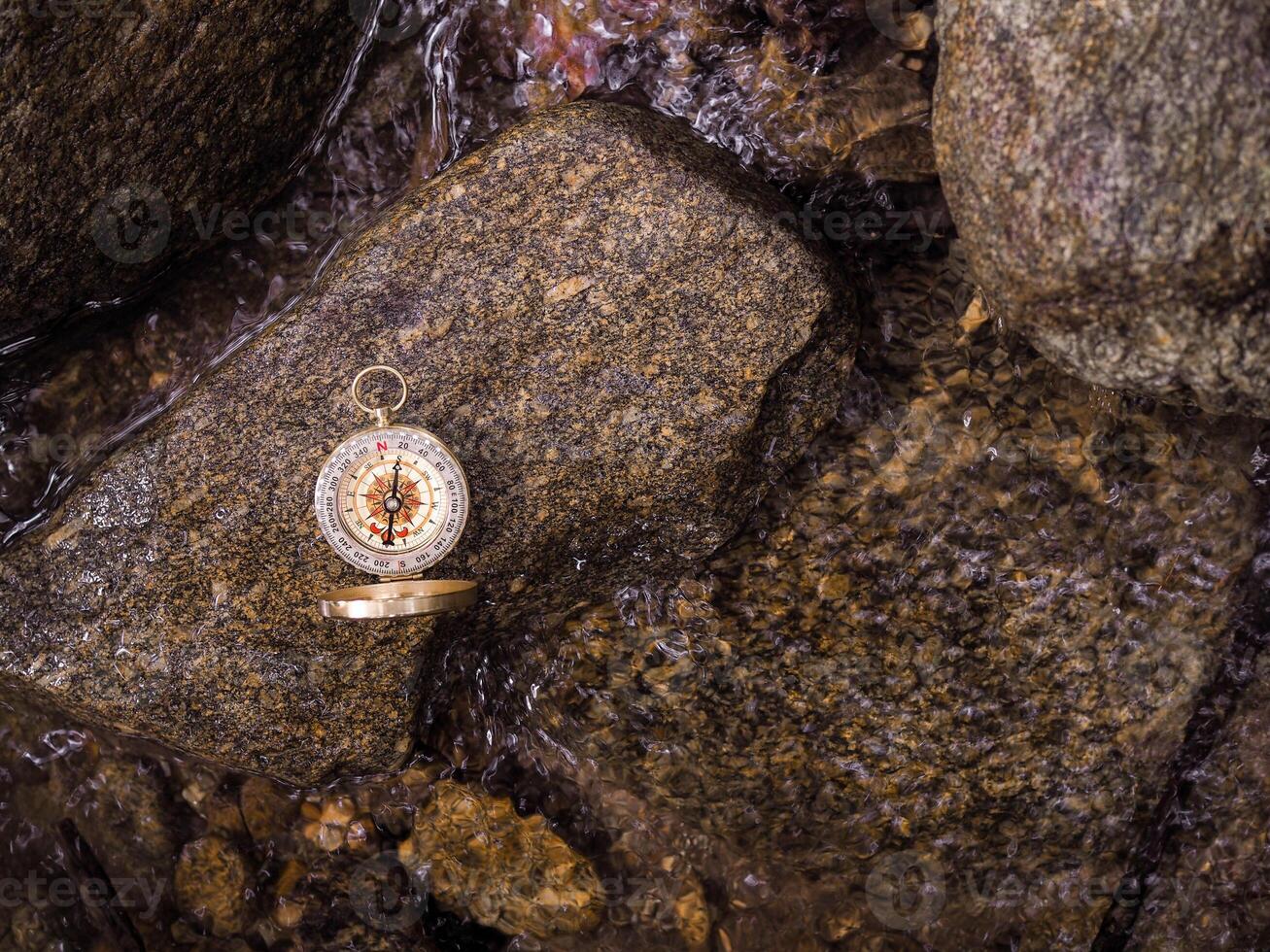 Compass on the rock with waterfall as background. The concept of world tourism day, Searching the right directions and Travel photo