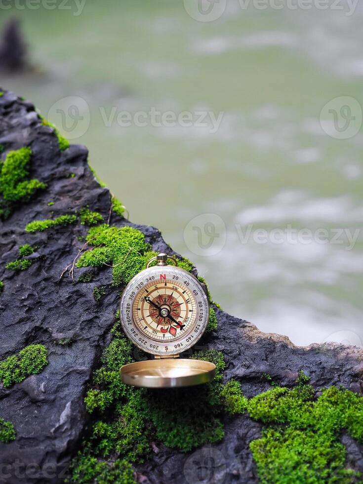Compass on the rock with waterfall as background. The concept of world tourism day, Searching the right directions and Travel photo