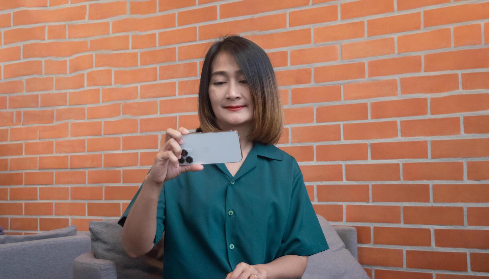 Asian woman sitting on the sofa holding their phones horizontally waching movie online at home on vacation, freedom lifestyle concepts. photo