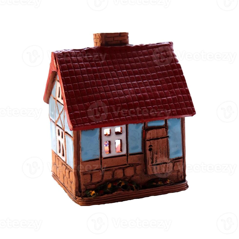 Ceramic candlestick in the form of a house with glowing windows from a candle inside - color photo, isolate for design photo