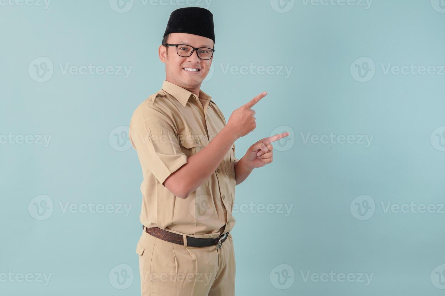 Happy Indonesian government worker man wearing khaki uniform pointing to the copy space beside him. photo