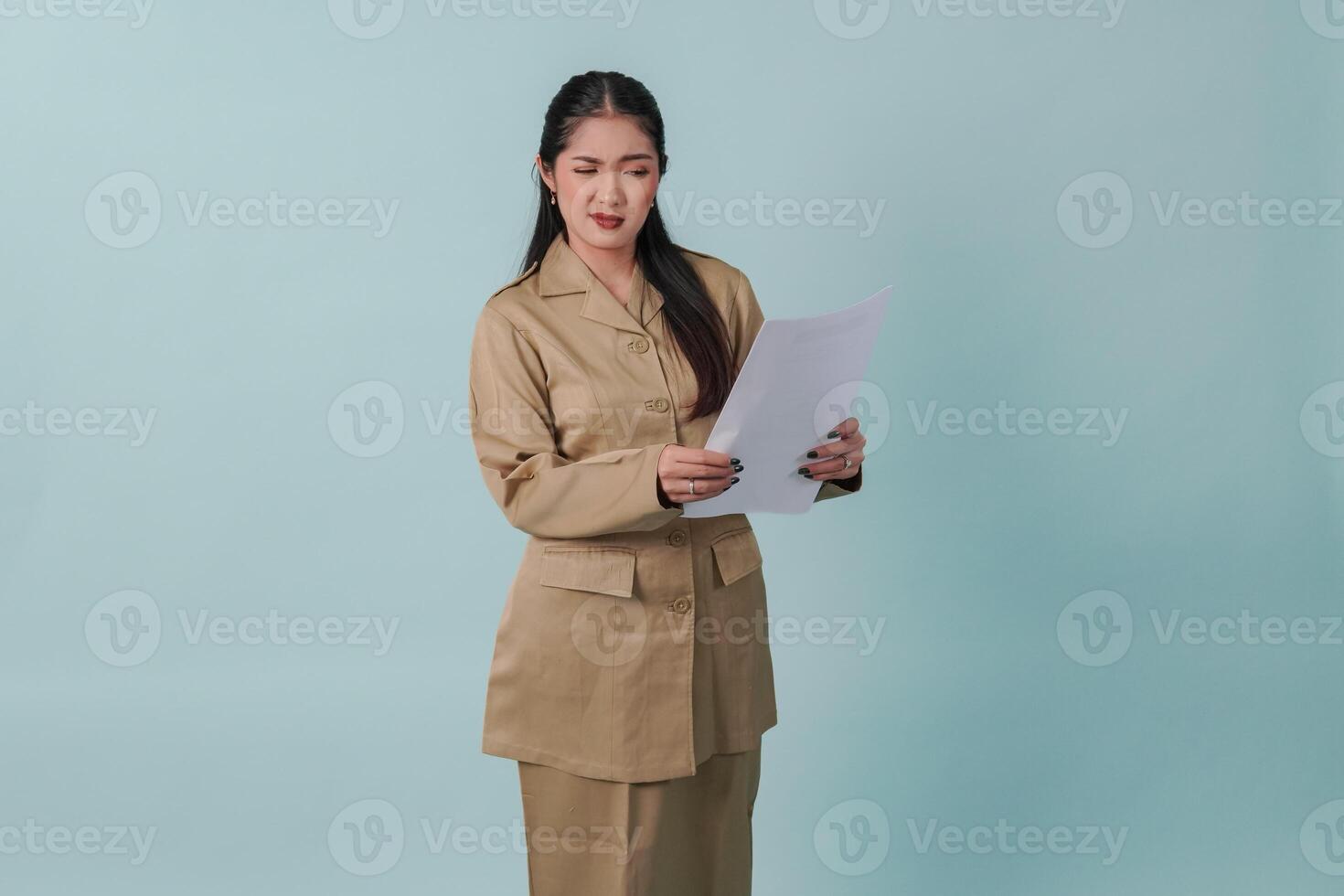 Indonesian government worker woman wearing khaki uniform reading document with doubting expression. photo