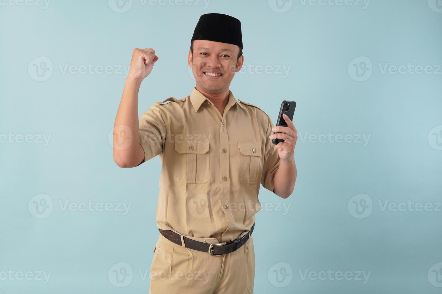 Indonesian government worker man holding smartphone with a happy successful expression. photo