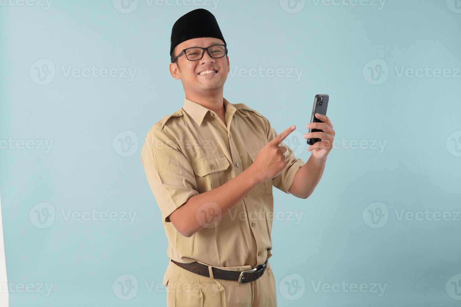 Happy government worker man wearing khaki uniform doing call while pointing to smartphone. photo