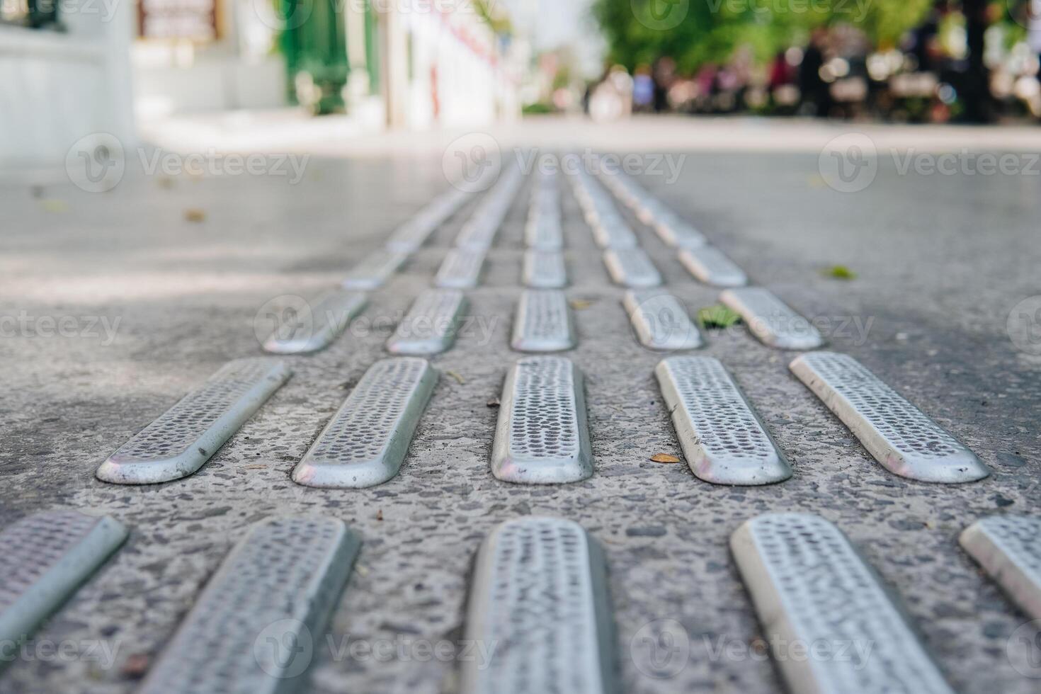 A close up of a sidewalk with a series of small metal slats. photo