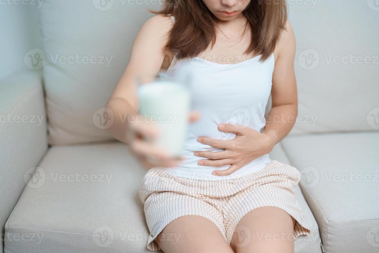 Lactose intolerance and Milk allergy concept. woman hold Milk glass and having abdominal cramps and pain when drink Cow Milk. Symptom stomach ache, Dairy intolerant, Nausea, Bloating, Gas and Diarrhea photo
