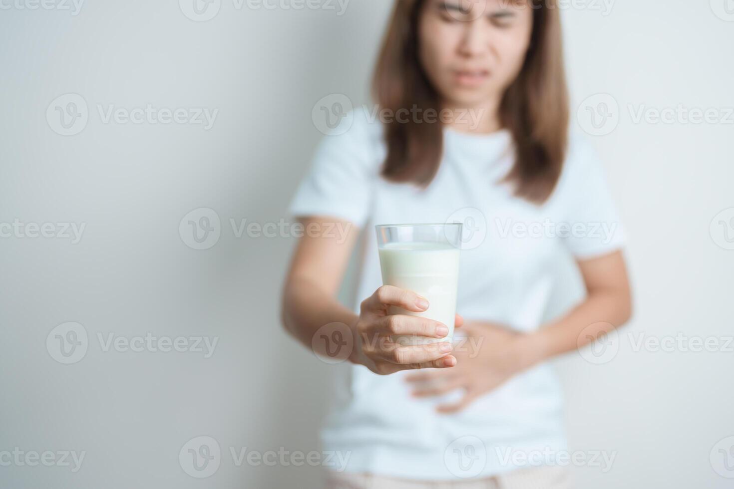 Lactose intolerance and Milk allergy concept. woman hold Milk glass and having abdominal cramps and pain when drink Cow Milk. Symptom stomach ache, Dairy intolerant, Nausea, Bloating, Gas and Diarrhea photo