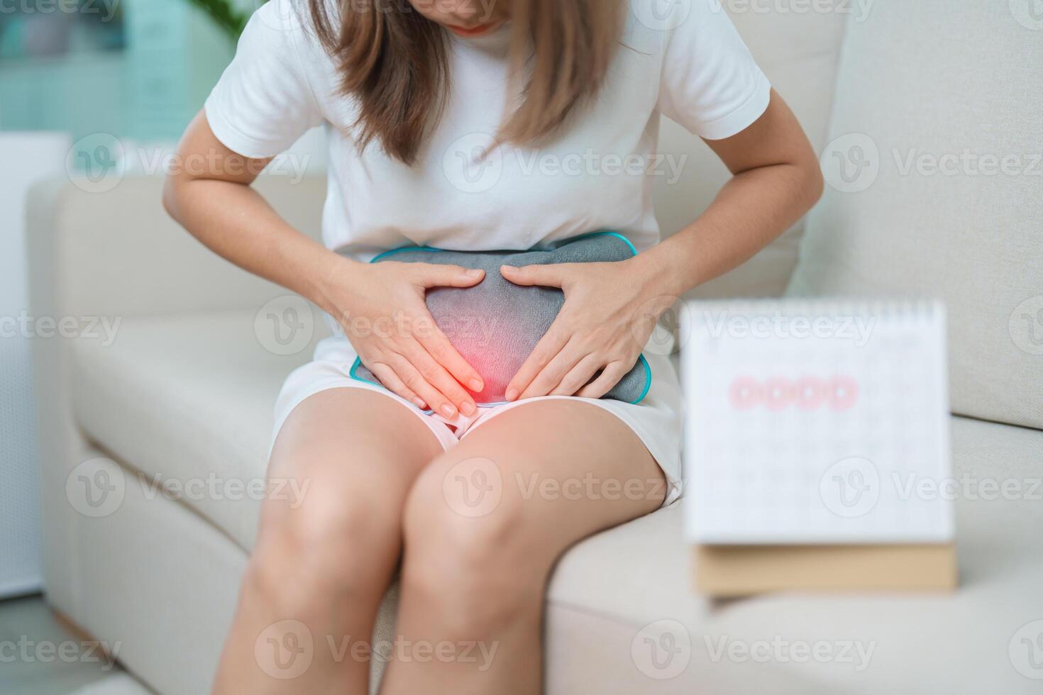 Menstruation period cycle of monthly and Stomachache concepts. woman having abdomen pain with hot water bottle and calendar, illness female suffer from premenstrual ache and body Health problem photo