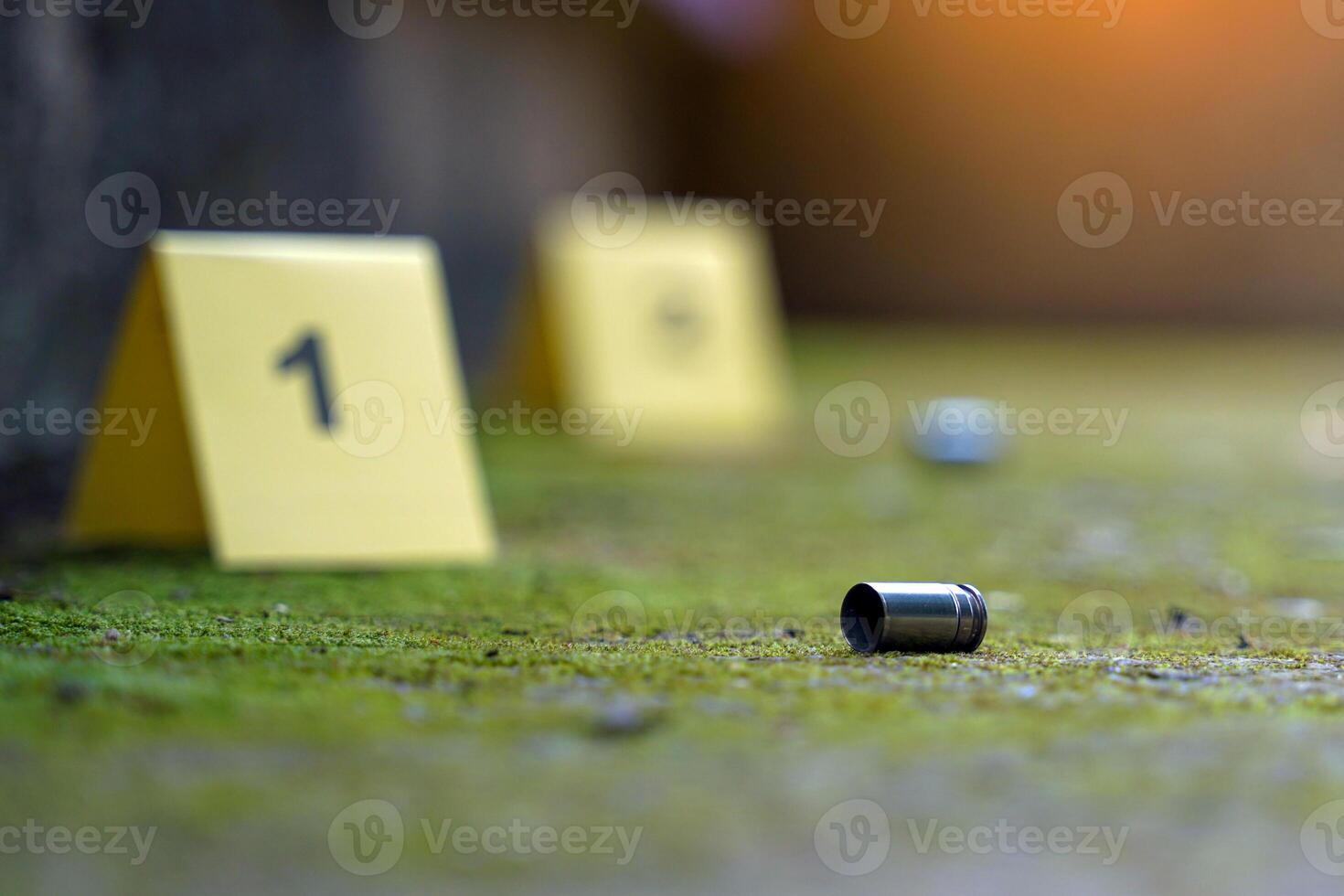 Bullet casings fell on the moss growing on the cement floor and blurry background of the evidence number plate at the scene. Concept of investigation, forensic science. photo