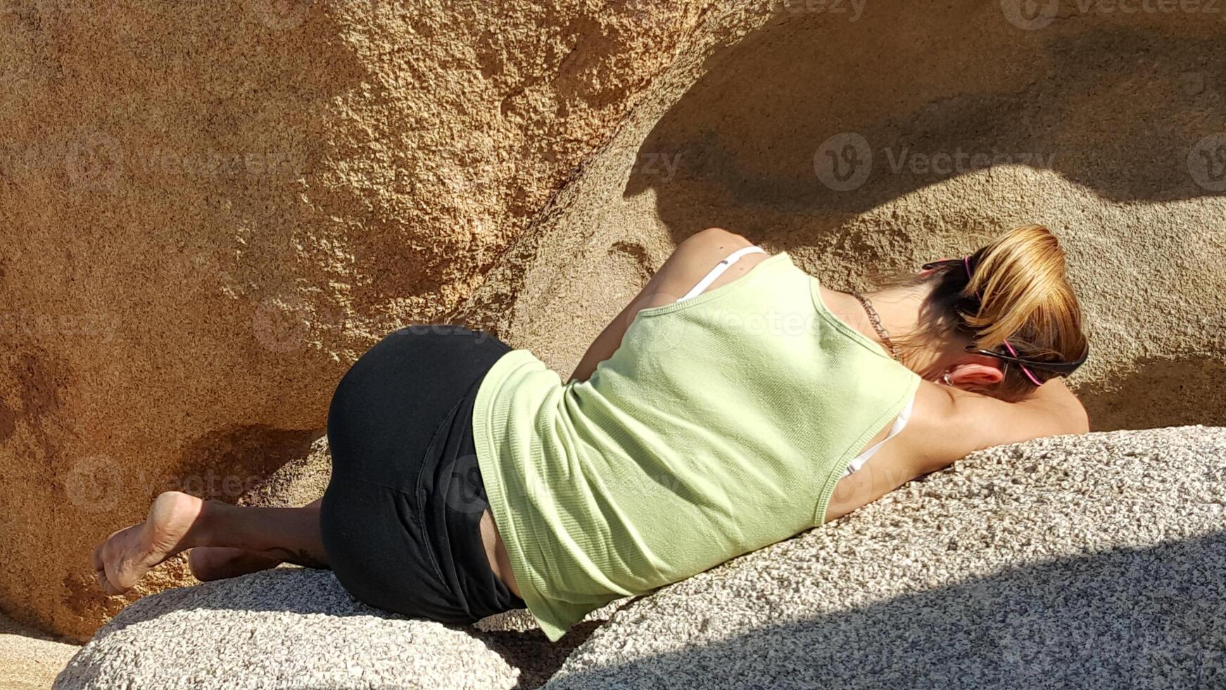 Back View of Fit Woman Laying on Boulders in California Sun photo