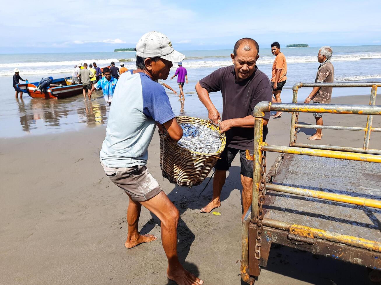 Pariaman, Indonesia - October 12, 2024 - Indonesian fishermen unloading freshly caught fish from their boats at Pariaman Beach, Indonesia. This scene captures the traditional fishing activity photo